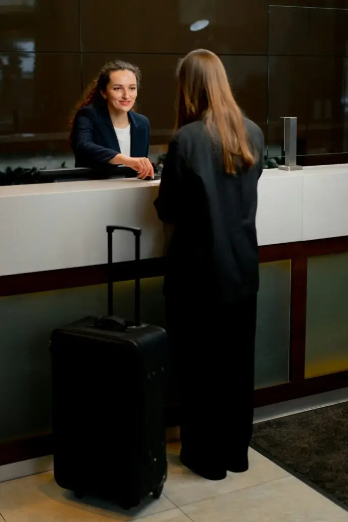 The receptionist at counter meets the guest with luggage in the hotel business travel hospitality